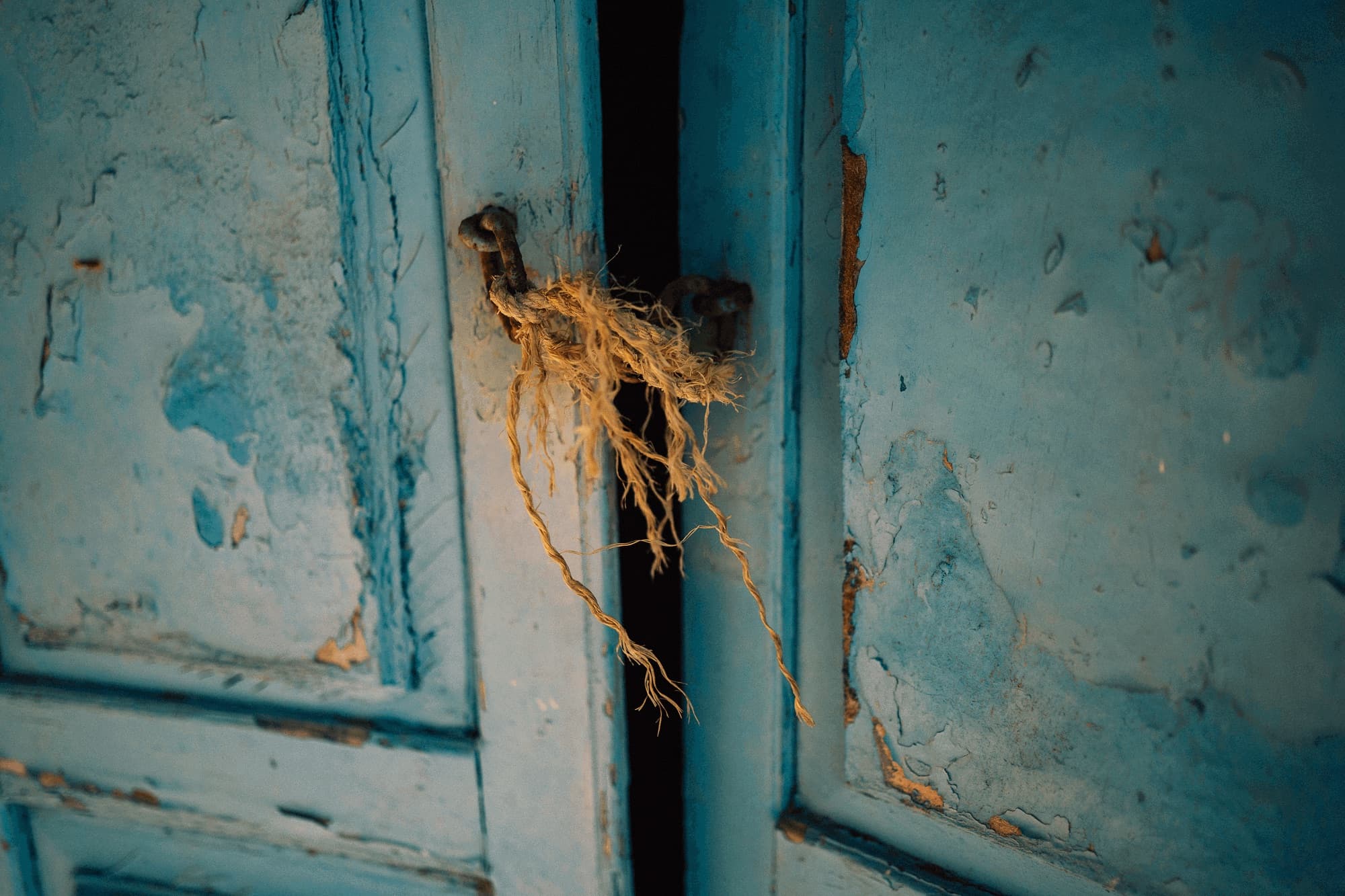 Frayed rope tying an old blue door shut