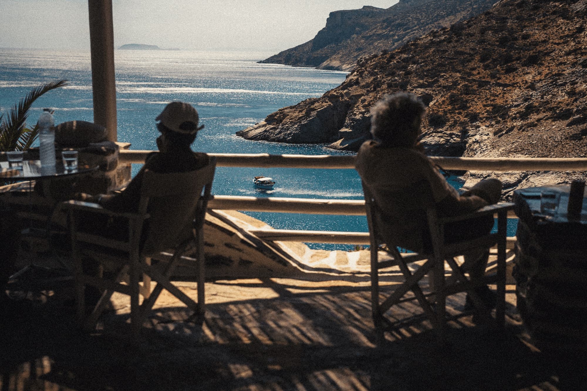 Two people in chairs on a terrace looking down at a bay