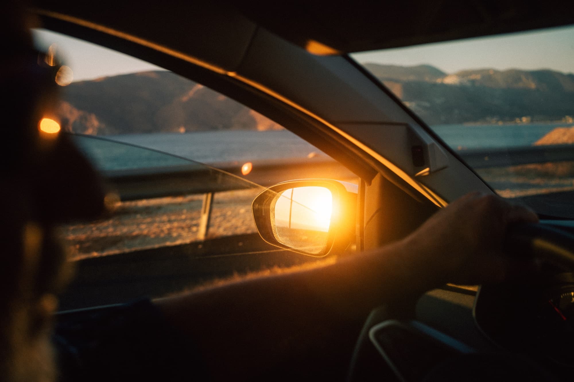 Sunset in a car's side mirror, seen from the passenger seat